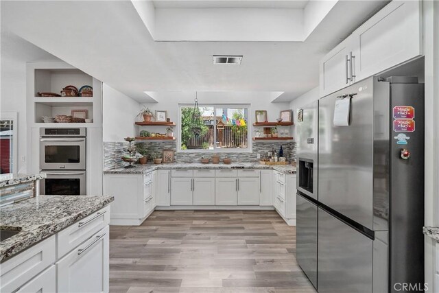 2981 Pembroke Cir, Corona, CA 92879 - kitchen with appliances with stainless steel finishes, open shelves, white cabinets, and light wood-style flooring