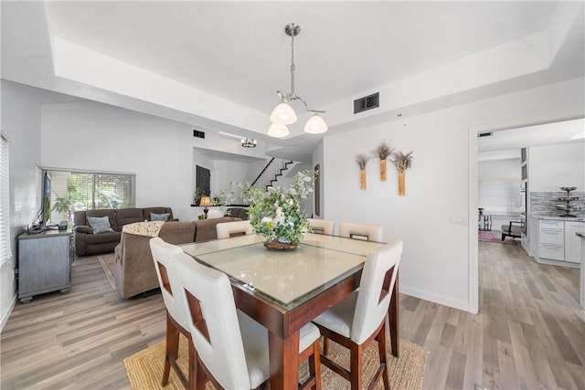 2981 Pembroke Cir, Corona, CA 92879 - dining area with stairs, light wood-style flooring, a chandelier, and a tray ceiling