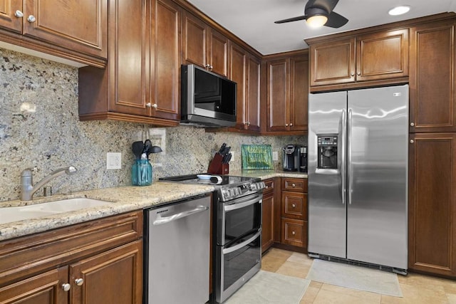 804 N The Strand Unit 11, Oceanside, CA 92054 - kitchen with appliances with stainless steel finishes, ceiling fan, backsplash, light stone countertops, and light tile patterned floors