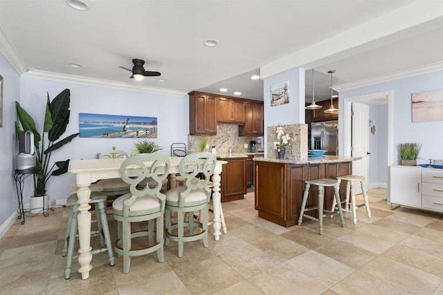 804 N The Strand Unit 11, Oceanside, CA 92054 - kitchen with stainless steel fridge, backsplash, brown cabinetry, ornamental molding, and a kitchen bar