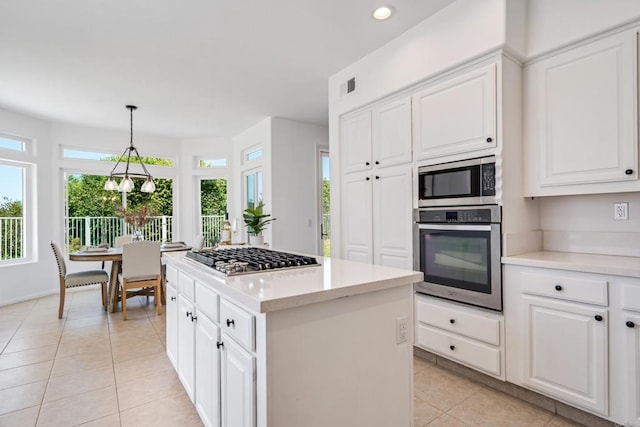 4926 Colusa Dr, Oceanside, CA 92056 - kitchen with appliances with stainless steel finishes, light tile patterned floors, light countertops, a kitchen island, and white cabinets