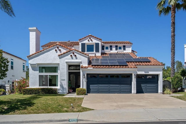 4926 Colusa Dr, Oceanside, CA 92056 - mediterranean / spanish home with roof mounted solar panels, driveway, a front lawn, a tile roof, and stucco siding
