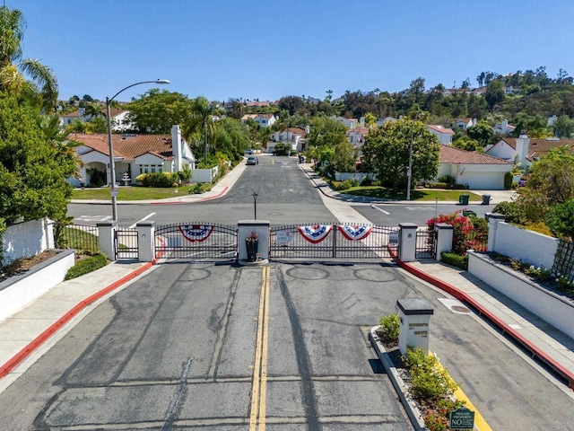 4926 Colusa Dr, Oceanside, CA 92056 - view of asphalt street with a gate, sidewalks, curbs, a residential view, and street lights