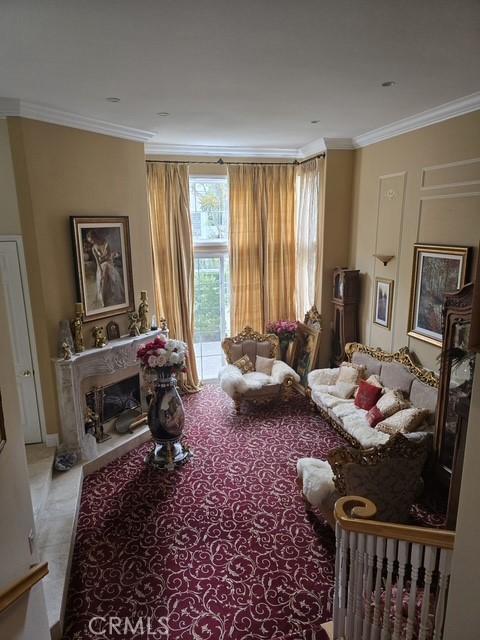11 Chandon, Newport Coast, CA 92657 - sitting room with crown molding, a large fireplace, and carpet floors