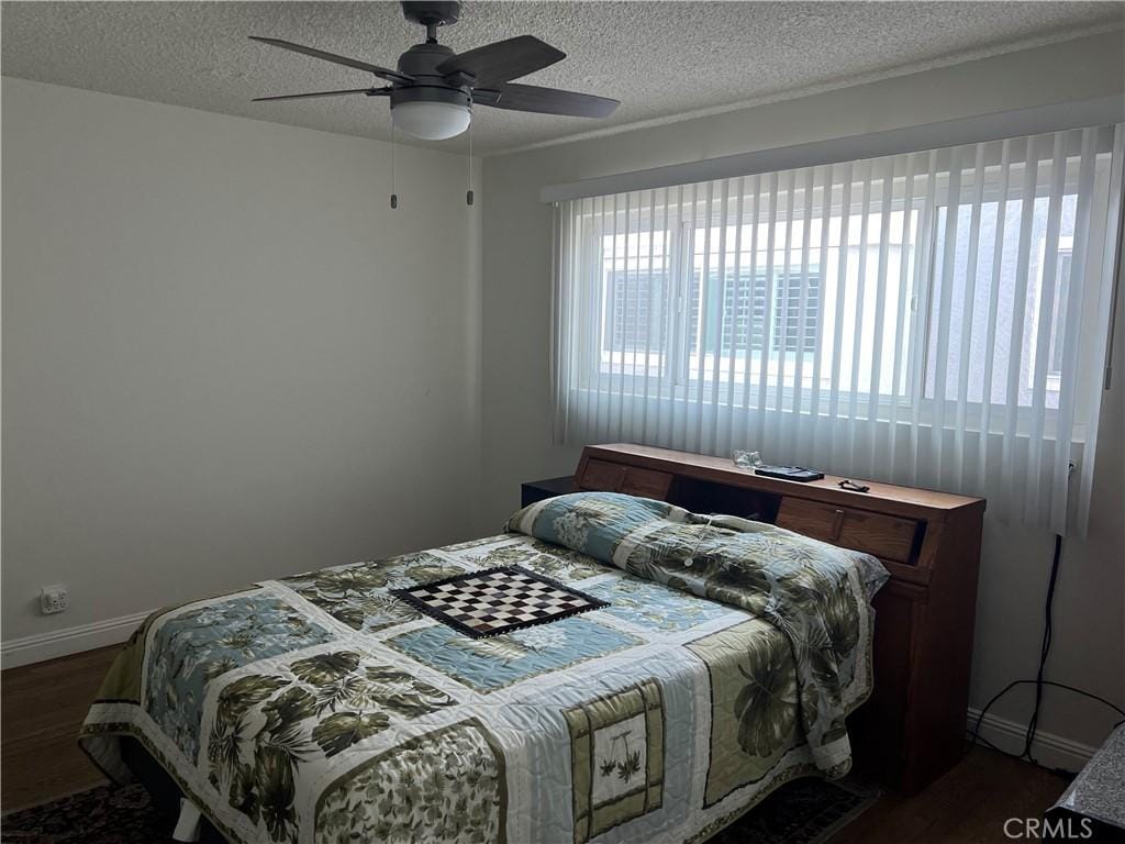 801 E 1st St Unit 15, Long Beach, CA 90802 - bedroom featuring dark wood-style floors, a textured ceiling, and a ceiling fan