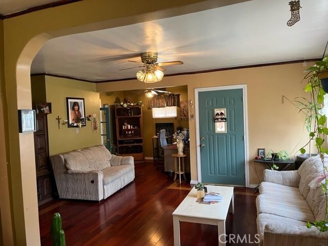 13567 Eldridge Ave, Sylmar, CA 91342 - living area featuring crown molding, arched walkways, wood finished floors, and a ceiling fan