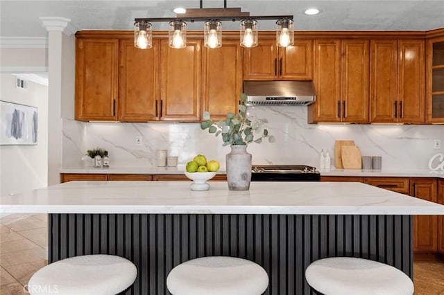 16186 Mount Gist Cir, Fountain Valley, CA 92708 - kitchen with under cabinet range hood, brown cabinetry, a kitchen island, a kitchen breakfast bar, and recessed lighting