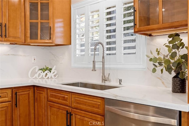 16186 Mount Gist Cir, Fountain Valley, CA 92708 - kitchen with stainless steel dishwasher, brown cabinetry, decorative backsplash, light stone counters, and glass insert cabinets