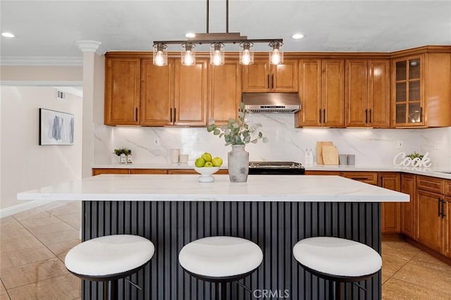 16186 Mount Gist Cir, Fountain Valley, CA 92708 - kitchen featuring under cabinet range hood, brown cabinetry, a kitchen bar, a center island, and recessed lighting