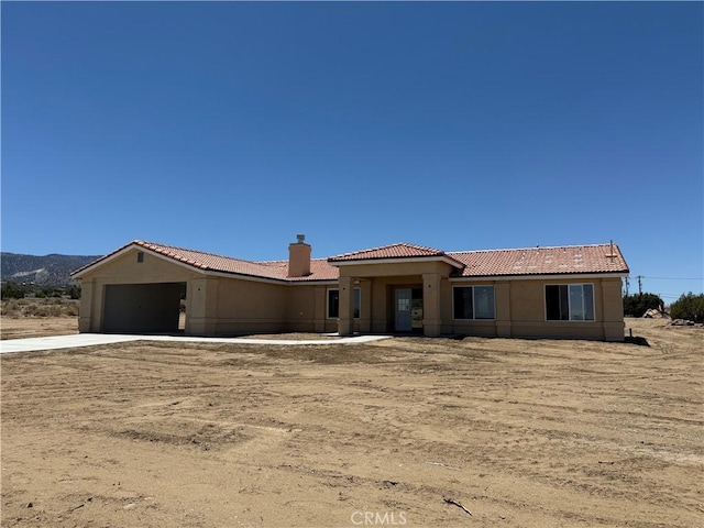9570 Mescalero Rd, Phelan, CA 92371 - view of front of home featuring a tiled roof, driveway, a garage, a chimney, and stucco siding