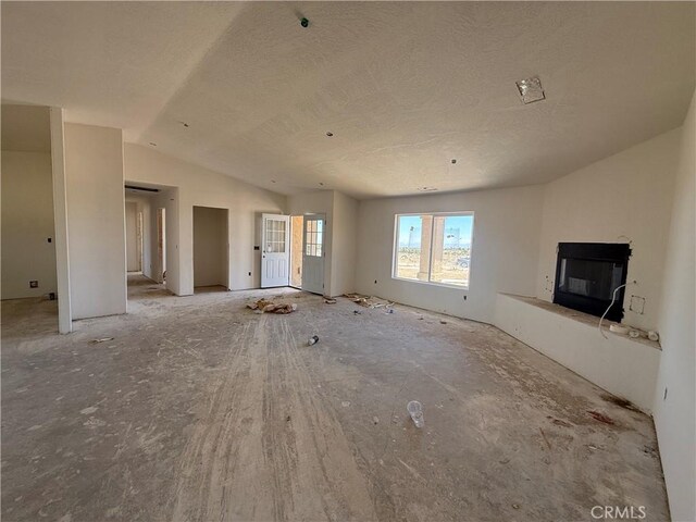 9570 Mescalero Rd, Phelan, CA 92371 - unfurnished living room with a glass covered fireplace, vaulted ceiling, and a textured ceiling