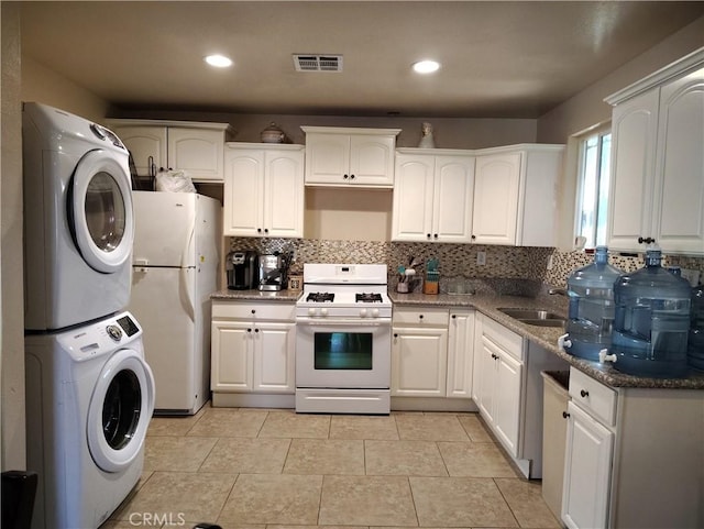 10815 Gorman Ave, Los Angeles, CA 90059 - kitchen with white appliances, estacked washer and dryer, decorative backsplash, white cabinets, and recessed lighting
