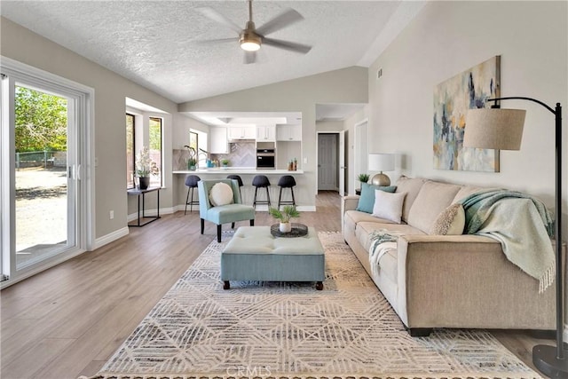 11969 Pinon Ave, Hesperia, CA 92345 - living area with vaulted ceiling, a ceiling fan, light wood-style floors, and a textured ceiling