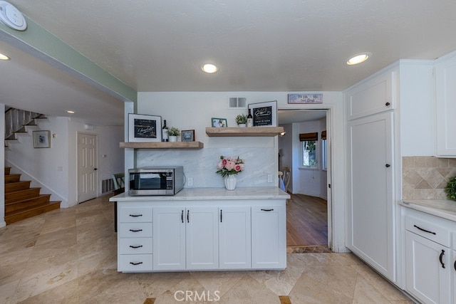 5035 Via Donaldo, Yorba Linda, CA 92886 - kitchen with stainless steel microwave, light countertops, white cabinetry, open shelves, and tasteful backsplash