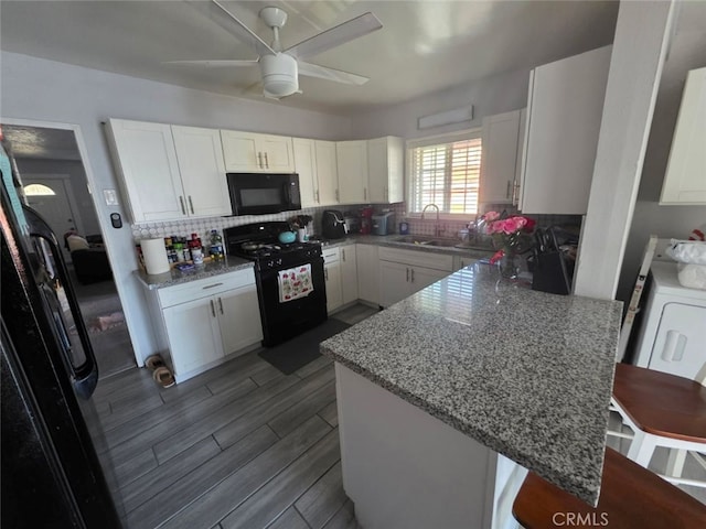 3424 E Cesar E Chavez Ave, Los Angeles, CA 90063 - kitchen with black appliances, a peninsula, a kitchen bar, white cabinetry, and decorative backsplash