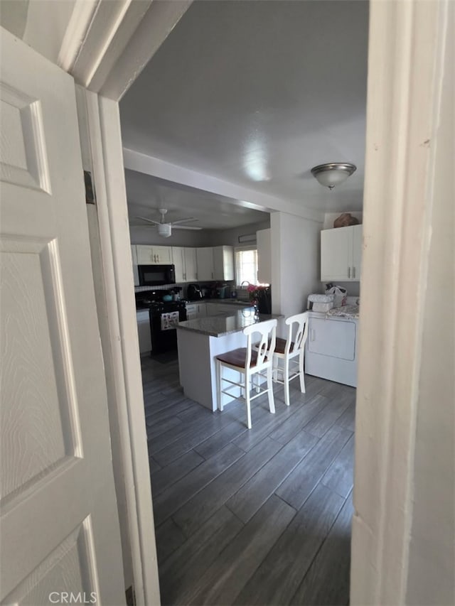 3424 E Cesar E Chavez Ave, Los Angeles, CA 90063 - kitchen with white cabinetry, dark wood-style flooring, black microwave, a kitchen breakfast bar, and separate washer and dryer