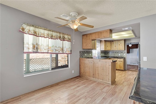 13491 Solitude Cir, Victorville, CA 92392 - kitchen with light wood-type flooring, dark countertops, a peninsula, ceiling fan, and plenty of natural light