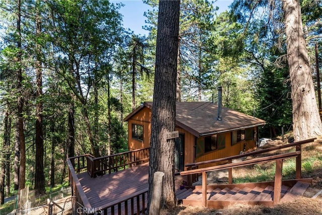 22490 Rockwell Rd, Cedarpines Park, CA 92322 - back of property with a wooden deck, a shingled roof, and a forest view