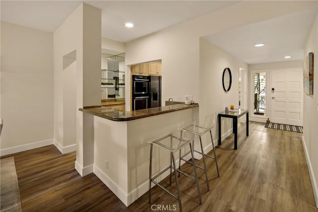 13078 Mindanao Way Unit 211, Marina Del Rey, CA 90292 - kitchen featuring dark wood-style floors, a breakfast bar, dark stone counters, recessed lighting, and fridge with ice dispenser