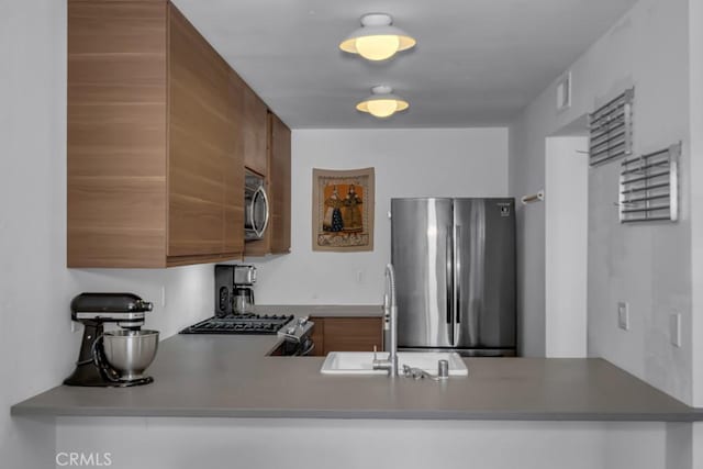 8939 Gallatin Rd Unit 116, Pico Rivera, CA 90660 - kitchen with stainless steel appliances, brown cabinets, and a peninsula
