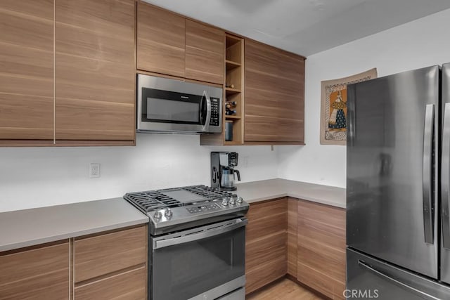 8939 Gallatin Rd Unit 116, Pico Rivera, CA 90660 - kitchen featuring appliances with stainless steel finishes, brown cabinetry, open shelves, modern cabinets, and light countertops