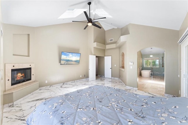 918 Reposado Dr, La Habra Heights, CA 90631 - unfurnished bedroom featuring arched walkways, a glass covered fireplace, high vaulted ceiling, connected bathroom, and a skylight
