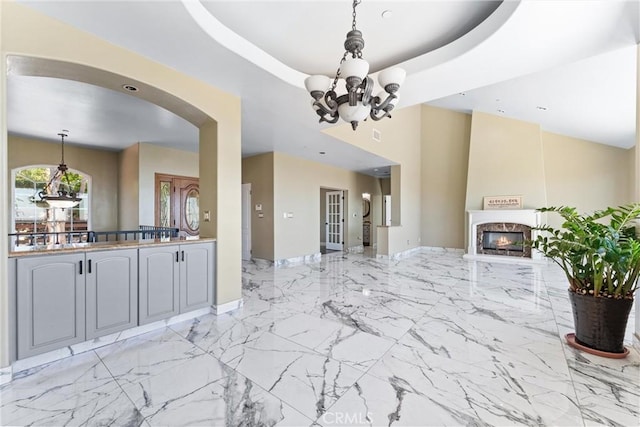 918 Reposado Dr, La Habra Heights, CA 90631 - kitchen with open floor plan, a chandelier, a lit fireplace, hanging light fixtures, and light marble finish floors