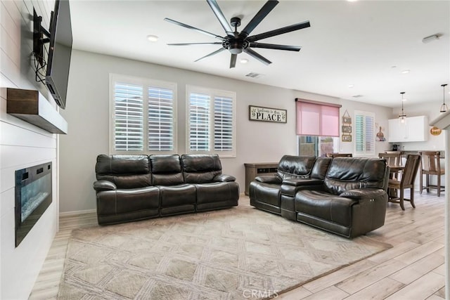 4989 River Ash Way, Fontana, CA 92336 - living room featuring a glass covered fireplace, a ceiling fan, recessed lighting, healthy amount of natural light, and light wood finished floors