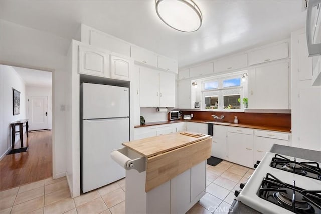 215 S Mason St, Arroyo Grande, CA 93420 - kitchen featuring freestanding refrigerator, white cabinets, a kitchen island, and light tile patterned floors