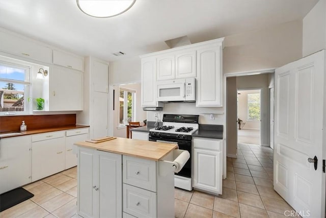 215 S Mason St, Arroyo Grande, CA 93420 - kitchen featuring white microwave, range with gas stovetop, light tile patterned flooring, white cabinets, and a kitchen island
