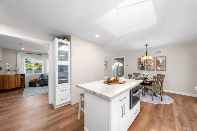 6270 Meadowcrest Dr, La Mesa, CA 91942 - kitchen with white cabinetry, light wood-style flooring, a breakfast bar area, a center island, and recessed lighting