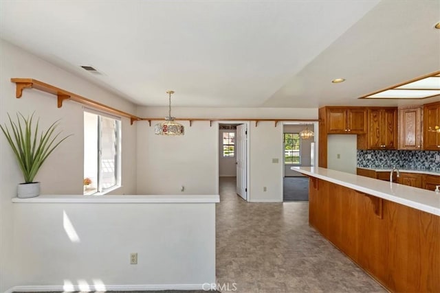 31655 Pio Pico Rd, Temecula, CA 92592 - kitchen with brown cabinets, light countertops, decorative backsplash, a breakfast bar area, and open shelves