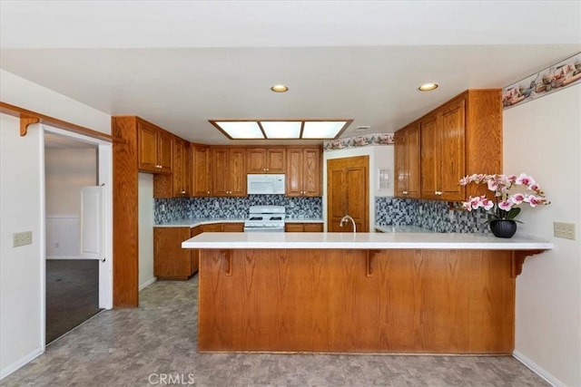 31655 Pio Pico Rd, Temecula, CA 92592 - kitchen with white appliances, brown cabinetry, a peninsula, light countertops, and decorative backsplash