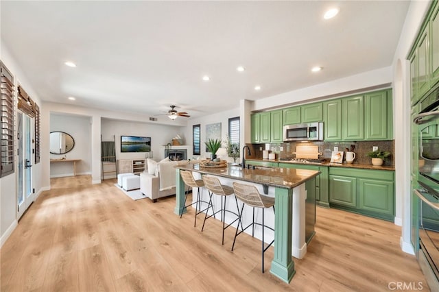 8 Caltrop Way, Ladera Ranch, CA 92694 - kitchen with green cabinets, appliances with stainless steel finishes, a kitchen breakfast bar, a fireplace, and recessed lighting
