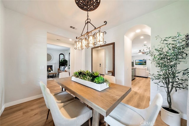8 Caltrop Way, Ladera Ranch, CA 92694 - dining area featuring light wood finished floors, arched walkways, a glass covered fireplace, and recessed lighting