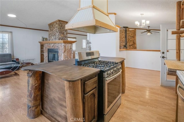 49750 Three Points Rd, Lancaster, CA 93536 - kitchen featuring stainless steel gas range oven, a fireplace, custom exhaust hood, light wood-style flooring, and crown molding