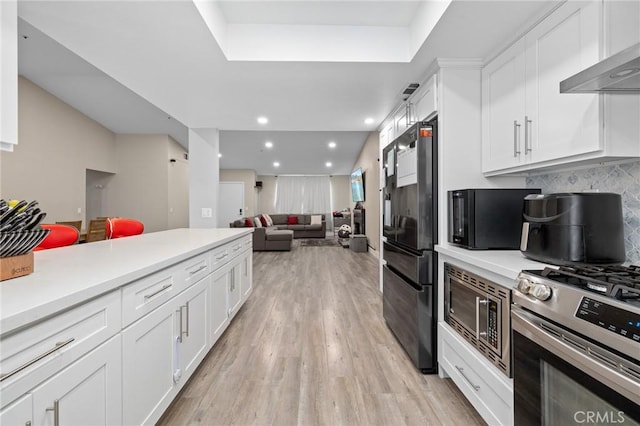 7550 Periwinkle Dr, Fontana, CA 92336 - kitchen with wall chimney exhaust hood, black appliances, white cabinets, light wood-style flooring, and light countertops