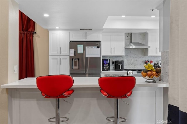 7550 Periwinkle Dr, Fontana, CA 92336 - kitchen featuring stainless steel appliances, wall chimney exhaust hood, white cabinets, a breakfast bar, and light countertops