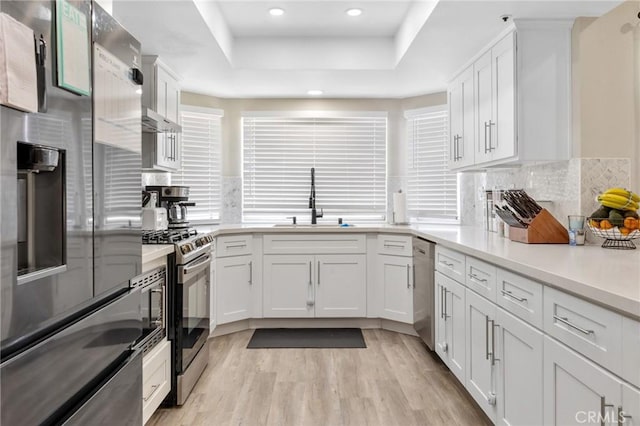 7550 Periwinkle Dr, Fontana, CA 92336 - kitchen featuring appliances with stainless steel finishes, a tray ceiling, white cabinetry, light wood-style floors, and light countertops