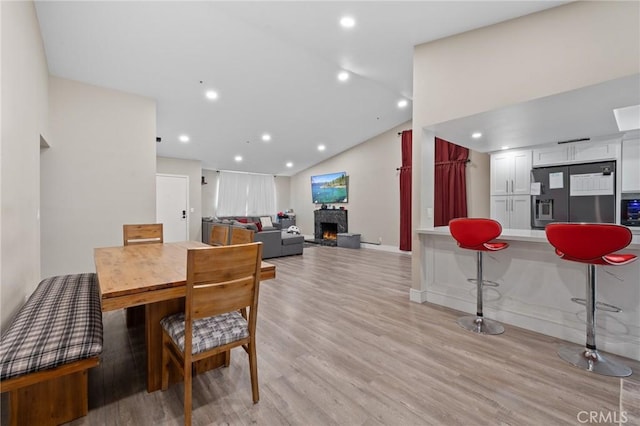 7550 Periwinkle Dr, Fontana, CA 92336 - dining area featuring vaulted ceiling, light wood-type flooring, recessed lighting, and a lit fireplace