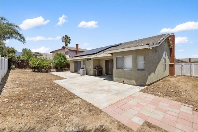 7550 Periwinkle Dr, Fontana, CA 92336 - back of property featuring stucco siding, a patio, a fenced backyard, and roof mounted solar panels
