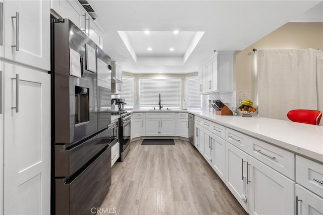 7550 Periwinkle Dr, Fontana, CA 92336 - kitchen featuring stainless steel appliances, light wood finished floors, a tray ceiling, white cabinets, and light countertops