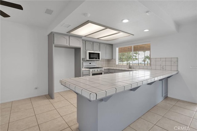 9191 White Rd, Phelan, CA 92371 - kitchen featuring gray cabinets, a peninsula, white appliances, backsplash, and recessed lighting