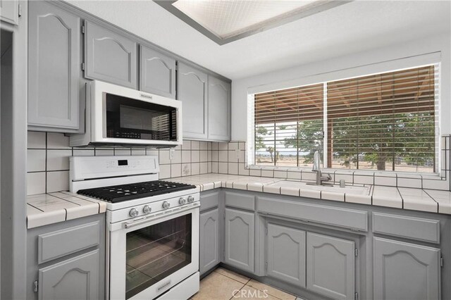 9191 White Rd, Phelan, CA 92371 - kitchen with gas range gas stove, stainless steel microwave, gray cabinetry, tile countertops, and tasteful backsplash