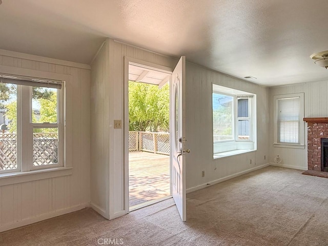 569 Huntington Rd, Cambria, CA 93428 - doorway to outside featuring carpet floors, a fireplace, wood walls, and a textured ceiling