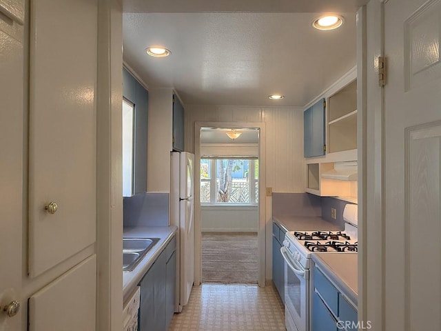 569 Huntington Rd, Cambria, CA 93428 - kitchen featuring white appliances, open shelves, light floors, blue cabinets, and light countertops