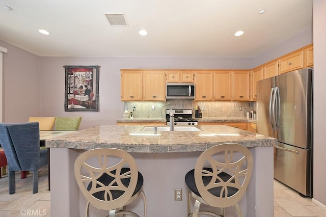 11180 Bridgefield Ct, Riverside, CA 92505 - kitchen with appliances with stainless steel finishes, tile counters, light brown cabinetry, light tile patterned flooring, and a breakfast bar area