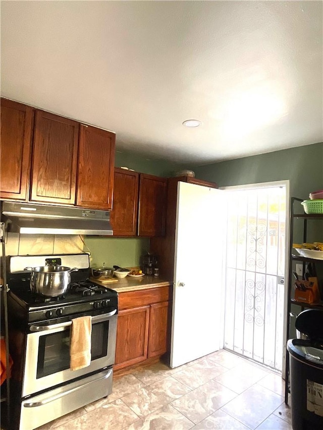 1130 S Rene Dr, Santa Ana, CA 92704 - kitchen with under cabinet range hood, stainless steel gas stove, and brown cabinets