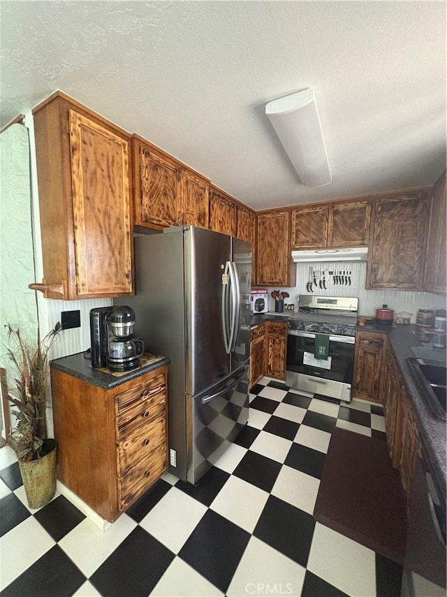 7103 Hanford Ave, Yucca Valley, CA 92284 - kitchen featuring appliances with stainless steel finishes, dark flooring, dark countertops, brown cabinets, and a textured ceiling