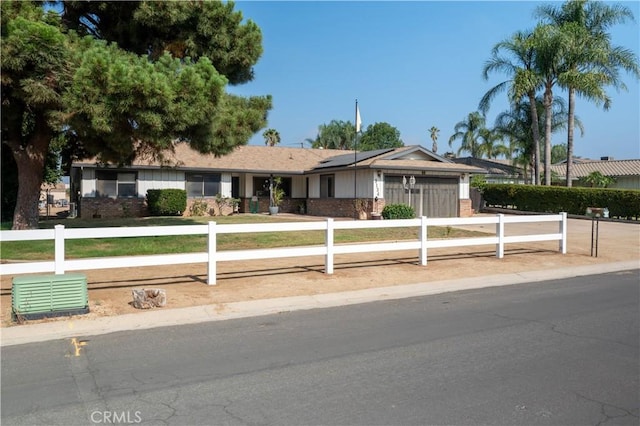 3134 Half Circle Rd, Norco, CA 92860 - ranch-style home with an attached garage, a fenced front yard, roof mounted solar panels, concrete driveway, and brick siding